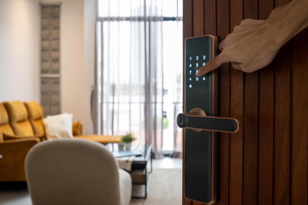 Mão digitando senha em fechadura digital moderna em porta residencial